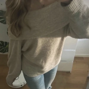 Stickad offshoulder tröja - Säljer en mysig beige/ljusgrå offshoulder tröja med långa ärmar. Perfekt för en avslappnad stil och kan matchas med jeans för en snygg look. Storlek M, skickar mer bilder vid intresse, använd en gång💗 Färgen stämmer inte jättebra överens med verkligheten då den är lite mer grå aktig💗