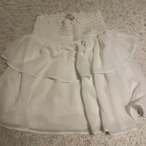Vit kjol från Chelsea - Säljer en vit kjol från Chelsea med volangdetaljer, den har en liten defekt på baksidan som ni kan se på bild 3❣️