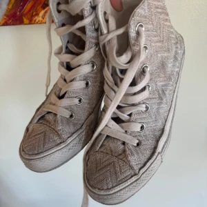  sneakers från Converse x Missoni glitter  - Snygga beige sneakers från Converse i samarbete med Missoni. Skorna har ett unikt zickzackmönster och klassisk snörning. Perfekta för dig som vill ha en stilren men ändå iögonfallande look.