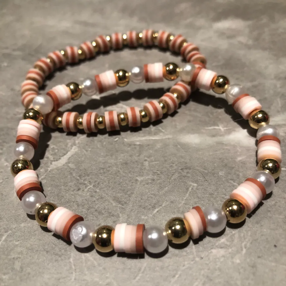 Två elastiska armband med färgglada pärlor i rosa, beige och vita nyanser. Armbanden har även guldfärgade och vita pärlor som ger en elegant touch. Perfekt för att liva upp vilken outfit som helst! 100kr för båda två 50 kr för ett. Asusteet.