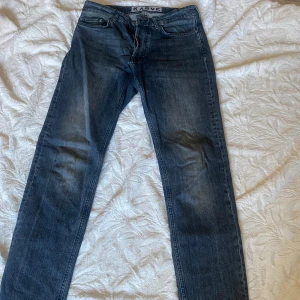 Blå jeans från Karve - Snygga blå jeans från Karve med en klassisk straight passform. De har en dragkedja och knappar framtill. Perfekta för en avslappnad stil. Har hål i en av fickorna. 