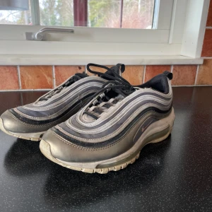 Nike Air Max sneakers i grå och silver - Säljer ett par klassiska Nike Air Max sneakers i grå och silver. Skorna har en vågig design med snörning och  luftdämpning i sulan för extra komfort.