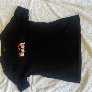 Svart t-shirt med tryck - Snygg svart t-shirt med ett coolt tryck i rött och vitt på framsidan. Perfekt för en avslappnad stil. Kortärmad och i en klassisk passform.