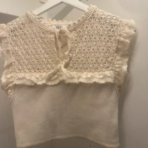 Stickad topp - Vit stickad topp från Zara med spetsdetaljer och volanger. Toppen har en knytning framtill och är ärmlös - Bara provad, aldrig använd💞💞