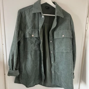 Grön manchesterjacka - Säljer en stilren grön manchesterjacka med knappar framtill. Jackan har två stora bröstfickor och långa ärmar. 