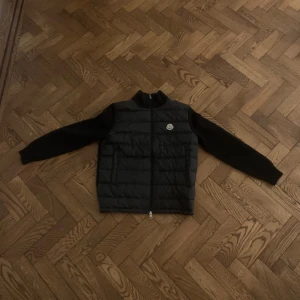 Svart cardigan från Moncler - Säljer en snygg, svart cardigan från Moncler i mycket bra skick. Perfekt för höst och vinter, håller dig varm och stilren. 🔥🍂Passar bra till både vardag och fest. Storleken är herr M.💯💯