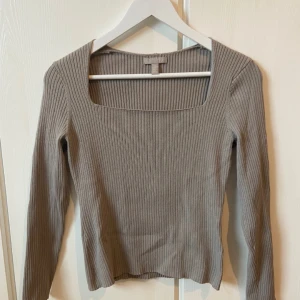 Beige ribbad tröja - Säljer en stilren beige ribbad tröja med fyrkantig halsringning. Tröjan har långa ärmar och är perfekt för både vardag och fest. Den är i mycket bra skick och passar perfekt till höst- och vårgarderoben.