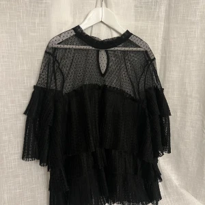 Svart transparent blus med volanger - Snygg svart blus i transparent material. Den har trekvarts ärmar och flera lager volanger❣️ Använd fåtal gånger så i väldigt bra skick. Köpt här på plock men kommer ursprungligen från cubus⭐️