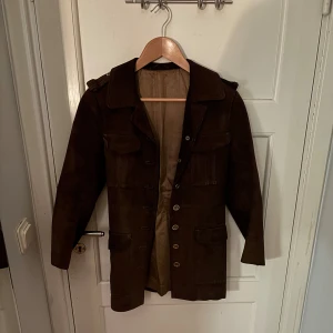 Vintage 70-tal - Äkta 70-tals kappa i mocka. Smått sliten på insidan men annars riktigt fin.  60 cm från axeln  35 cm över bröstet