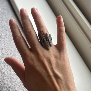 Zigzagformad ring i silver - Snygg och modern ring i silver med ett coolt zigzag-mönster. Perfekt för att ge din outfit en edgy touch. Passar både till vardags och fest. Ringen är i mycket bra skick och har en unik design som verkligen sticker ut.