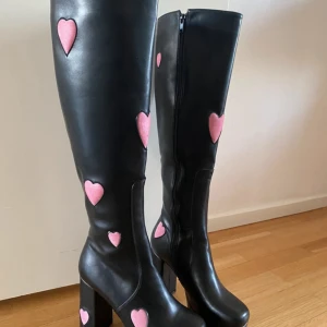 Svarta stövlar med rosa hjärtan - Superfina svarta stövlar från Lamoda med rosa hjärtan som detaljer. De har en dragkedja på sidan för enkel på- och avtagning. Perfekta för att ge en söt men kaxig touch till din outfit! 🖤💖