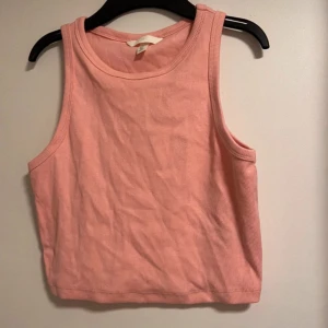 Rosa ribbad linnetopp - Säljer en söt rosa ribbad linnetopp i mycket bra skick. Perfekt för sommardagar eller som ett lager under en jacka. Toppen är ärmlös och har en croppad passform som ger en avslappnad stil. Oanvänd