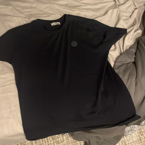 Svart t-shirt från Moncler - Säljer en stilren svart t-shirt från Moncler i storlek M. Den har en diskret logga på bröstet och är tillverkad i mjukt material för en bekväm passform. Perfekt för både vardag och fest!