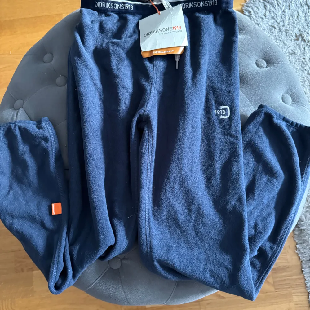 Säljer ett par mörkblå fleecebyxor från Didriksons i nytt skick, lappar på. . Byxorna har en elastisk midja med märkets logga och en liten orange detalj vid benet. Superbekväma och stilrena för både inomhus och utomhus.. Farkut & Housut.