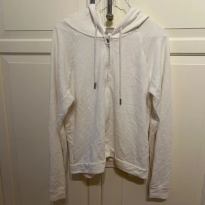 Vit hoodie från H&M - Säljer en vit hoodie från H&M i storlek S. Den är supermjuk och har en dragkedja framtill. Perfekt för en chill dag eller som ett extra lager under jackan. Den har en klassisk passform med långa ärmar och en justerbar huva. 🕶️