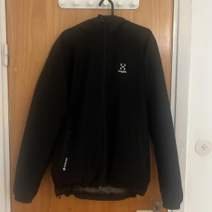 Svart jacka från Haglöfs - Säljer en svart jacka från Haglöfs i ny skick. Den har en dragkedja framtill och är långärmad. Perfekt för höst och vår med sitt lätta och funktionella material. Jackan har en stilren design och är idealisk för både vardag och utomhusaktiviteter. Den har gore-tex så den är helt vattentät och vindtät.