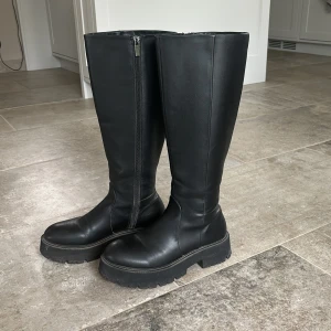 Svarta stövlar med dragkedja - Snygga svarta stövlar i skinn med dragkedja på sidan. Perfekta för höst och vinter med en robust sula som ger bra grepp. De har en klassisk design som passar till både vardag och fest. Nypris runt 700-800kr. 