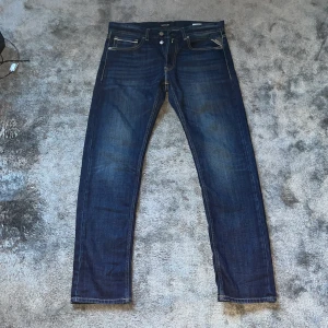 Mörkblå jeans från Replay - Säljer ett par snygga mörkblå jeans från Replay. De har en snygg slim fit, femficks design. Perfekt nu till kallare väder. Storlek 32:32. Nypris : 1900 En knapp på gylfen fattas men inget som förhindrar funktionen eller skicket