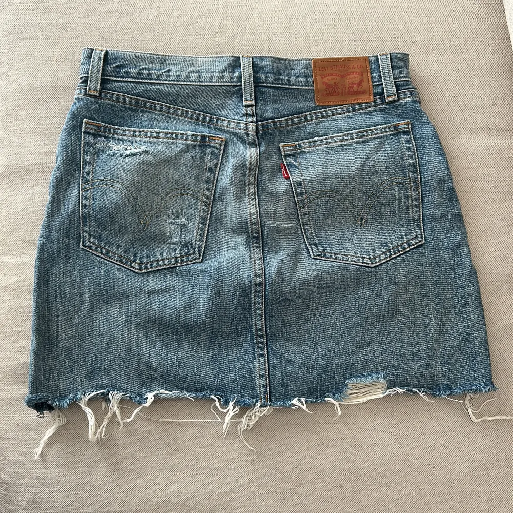 Säljer en jeanskjol från Levi's i en klassisk blå denim med slitna detaljer. . Kjolar.