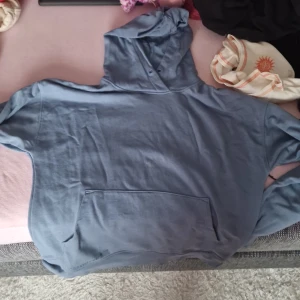 Blå hoodie - Säljer en skön blå hoodie med en stor ficka fram. Perfekt för mysiga dagar eller som en extra lager när det är lite kyligt. Den har en klassisk passform och en luva för extra komfort.