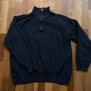 Svart ribbad tröja från Dobber - Säljer en mörkgrå ribbad half zip-tröja från Dobber i storlek XL. Den har en dragkedja vid halsen och är perfekt för kyliga dagar. Tröjan är långärmad och superbekväm. Hör av dig om du är intresserad!