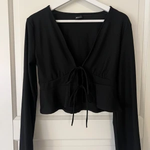 Svart knyttröja - Svart tröja med knytning. Långa vida ärmar. Går att ha både med eller utan topp under. Använd fåtal gånger.