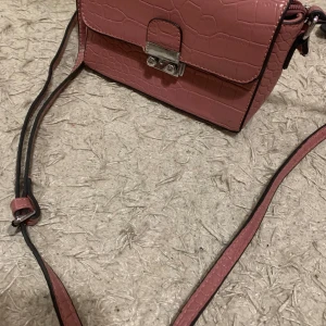 Smutsrosa hand/axelväska - Väskan är jätte stilig och har mycket utrymme för dina föremål.  Den är nästan helt oanvänd och perfekt för dig som vill ha en pop av färg i din outfit!