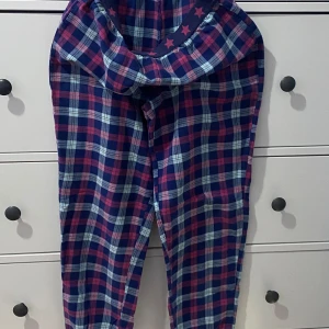 Rutig pyjamasbyxa i blå och rosa - Supermysiga pyjamasbyxor med ett klassiskt rutigt mönster i blått och rosa. Byxorna har en bekväm passform och är gjorda i mjukt material. De har en elastisk midja, använd några gånger. 