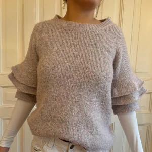  stickad tröja med volang  - Stickad tröja med snygga volanger! Tröjan passar mer en M och hon på bilden är en S! Tröjan har silvriga detaljer🩷