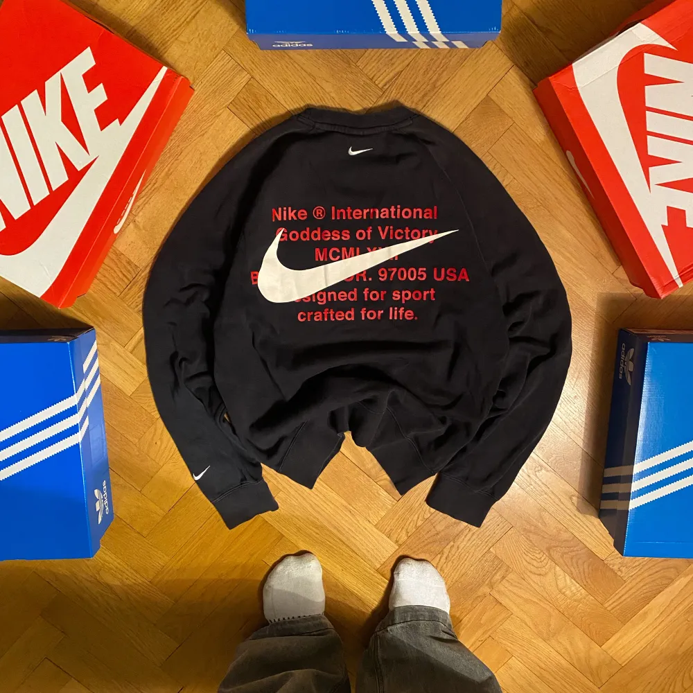 Säljer en svart sweatshirt från Nike i storlek S. Tröjan har en stor vit Nike-logga och röd text på baksidan som ger en sportig look och dubbel logga där fram. Materialet känns mjukt och bekvämt. Passar perfekt för hösten! . Tröjor & Koftor.