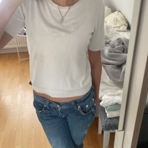 Vit kortärmad topp från H&M - Säljer en enkel och stilren vit topp från H&M. Den är kortärmad och har en normal passform. Perfekt för vardagsbruk eller att styla upp med accessoarer. Har e. Liten smink fläck vid halsen.💕