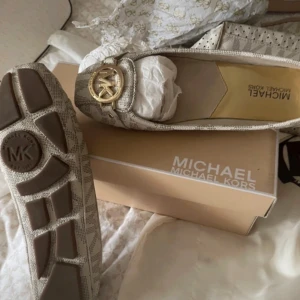 Michael Kors ballerinaskor - Säljer ett par snygga beigea/vita ballerinaskor från Michael Kors. Skorna är i nyskick och kommer i originalförpackning. Nypris 1010. Perfekta för både vardag och fest!