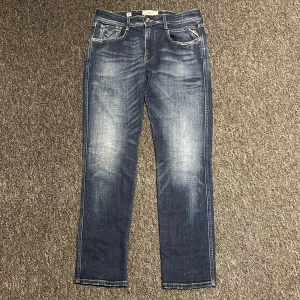 Replay jeans - Säljer ett par snygga blå jeans från Replay i  riktigt bra skick. De har en klassisk femficksdesign med snygga slitningar för en cool look. Perfekta för både vardag och fest! De är använda typ 3 gånger så skicket är riktigt bra! slim fit. Stl: W32 L30. 