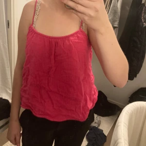 Rosa ärmlös topp - Säljer en söt rosa ärmlös topp med smala axelband. Perfekt för sommardagar eller som ett lager under en kofta. Toppen har en lös passform och är gjord i ett lätt och bekvämt material.