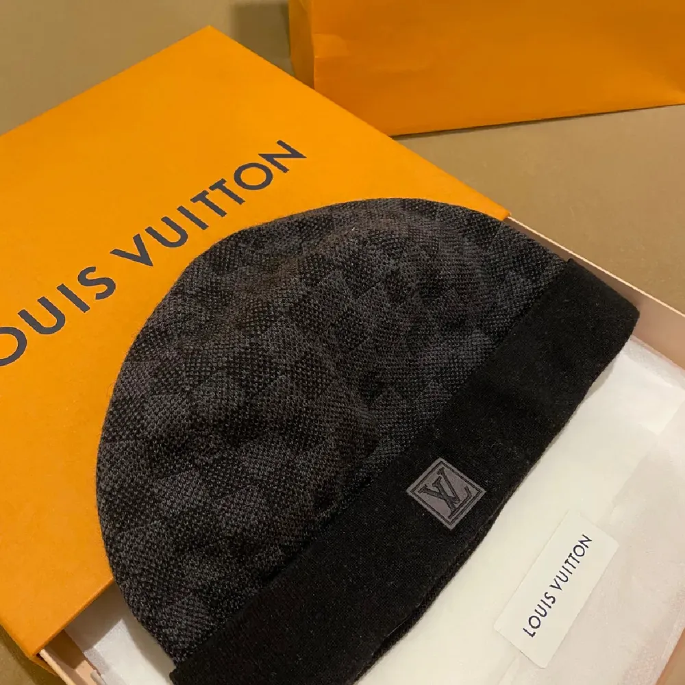 Säljer en snygg svart mössa från Louis Vuitton med klassiskt rutmönster. Mössan är i mycket bra skick och kommer i originalförpackning. Perfekt för höst och vinter, och den har en diskret LV-logga framtill. Passar både till vardags och lite finare tillfällen.. Accessoarer.