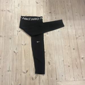 Säljer ett par svarta Nike Pro leggings i Dri-FIT material. De är högmidjade med en elastisk midja och har en liten Nike-logga på benet. Perfekta för träning eller vardagsbruk. Superbekväma och i super bra skick! 