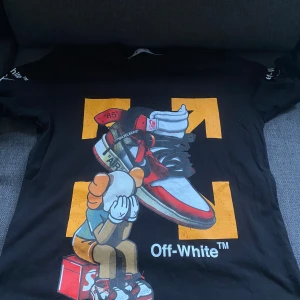 Svart t-shirt från Off-White - Cool svart t-shirt från Off-White med ett unikt tryck av en tecknad figur som sitter på en Supreme-låda. T-shirten har Off-White-loggan och detaljer i rött, orange och vitt. Perfekt för streetwear-stilen!