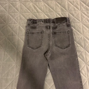 Grå bootcut jeans från Grunt - Säljer ett par snygga grå bootcut jeans från Grunt. De har en klassisk femficksdesign och en knapp med märkets logga. Perfekta för både vardag och fest! 🖤