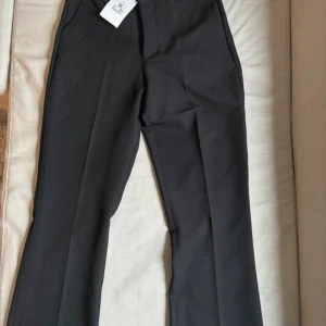 Svarta kostymbyxor - Snygga svarta kostymbyxor i nytt skick. Perfekta för både formella tillfällen och vardagsbruk. De har en klassisk straight passform och är gjorda i ett bekvämt material som ger en stilren look. Passar utmärkt till en skjorta eller en mer avslappnad tröja.