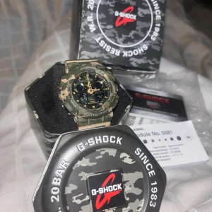 G-Shock klocka i kamouflage - Säljer en robust G-Shock klocka från Casio i kamouflagefärg. Den är stöttålig, magnetresistent och vattentät upp till 20 BAR. Klockan har funktioner som stoppur, timer, alarm, världstid och auto LED-bakgrundsbelysning. Perfekt för äventyr och vardag! Den är använd några gånger men orginalförpackning, manual, lapp är kvar, lite av den vita färgen på texten har nöts bort men annars inget fel på den🫶🏽fler bilder går å lösa, pris kan diskuteras vid snabb affär 