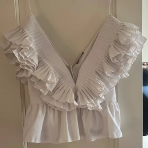 Vit volangtopp - Säljer en superfin vit topp med volanger och djup v-ringning från zara 
