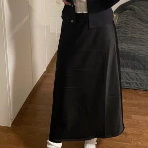 Svart långkjol - Säljer en stilren svart långkjol i mycket bra skick. Kjolen har en klassisk design som passar perfekt för både vardag och fest. Den är gjord i ett mjukt och bekvämt material som faller snyggt. Perfekt för höst och vinter! Använd flitigt men i bra skick! Hör av er vid önskan om fler bilder<3