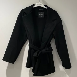 Svart kappa från Missay - Snygg svart kappa från Missay i bra skick. Den har en elegant knytning i midjan och långa ärmar. Perfekt för höst och vår när du vill se stilren ut. Passar både till vardags och fest! Den är köpt för 400 och den är lite nopprig så kan sänka priset till 250-300