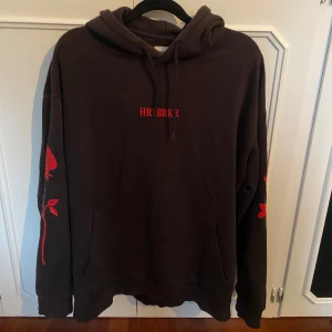 Svart hoodie från yourturn  - En svart hoodie med texten ”HRTBRKR” på och röda rosor vid ärmen. Använd ett par gånger men inga tecken på skador eller slitage.