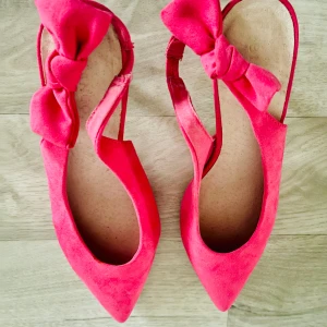 Rosa pumps med rosett - Säljer ett par snygga rosa pumps i mocka med spetsig tå och en söt rosett på sidan. Perfekta för festliga tillfällen! De har en elegant design och är i mycket bra skick. Passar perfekt till både klänning och byxor.