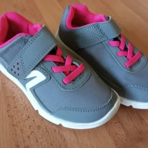 Grå och rosa sneakers för barn - Säljer ett par snygga och bekväma grå sneakers med rosa detaljer för barn. Skorna har en praktisk kardborreknäppning och rosa snörning. De är i mycket bra skick och perfekta för lek och vardag. Sulan är vit och ger bra grepp.