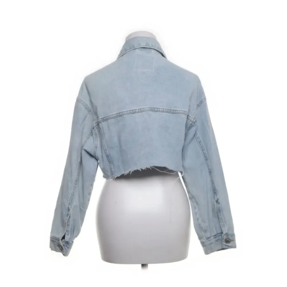 Säljer en supercool ljusblå croppad jeansjacka från Bershka. Jackan har en avslappnad passform och är perfekt för vår och sommar. Den har långa ärmar och en rå kant nedtill för en trendig look. Perfekt för att ge din outfit en edgy touch!. Takit.