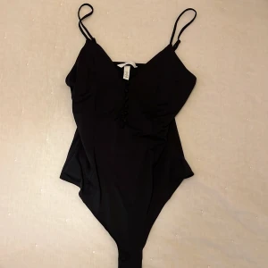 Svart body med smala axelband från H&M - Snygg svart body med smala axelband och en stilren design. Aldrig använd!