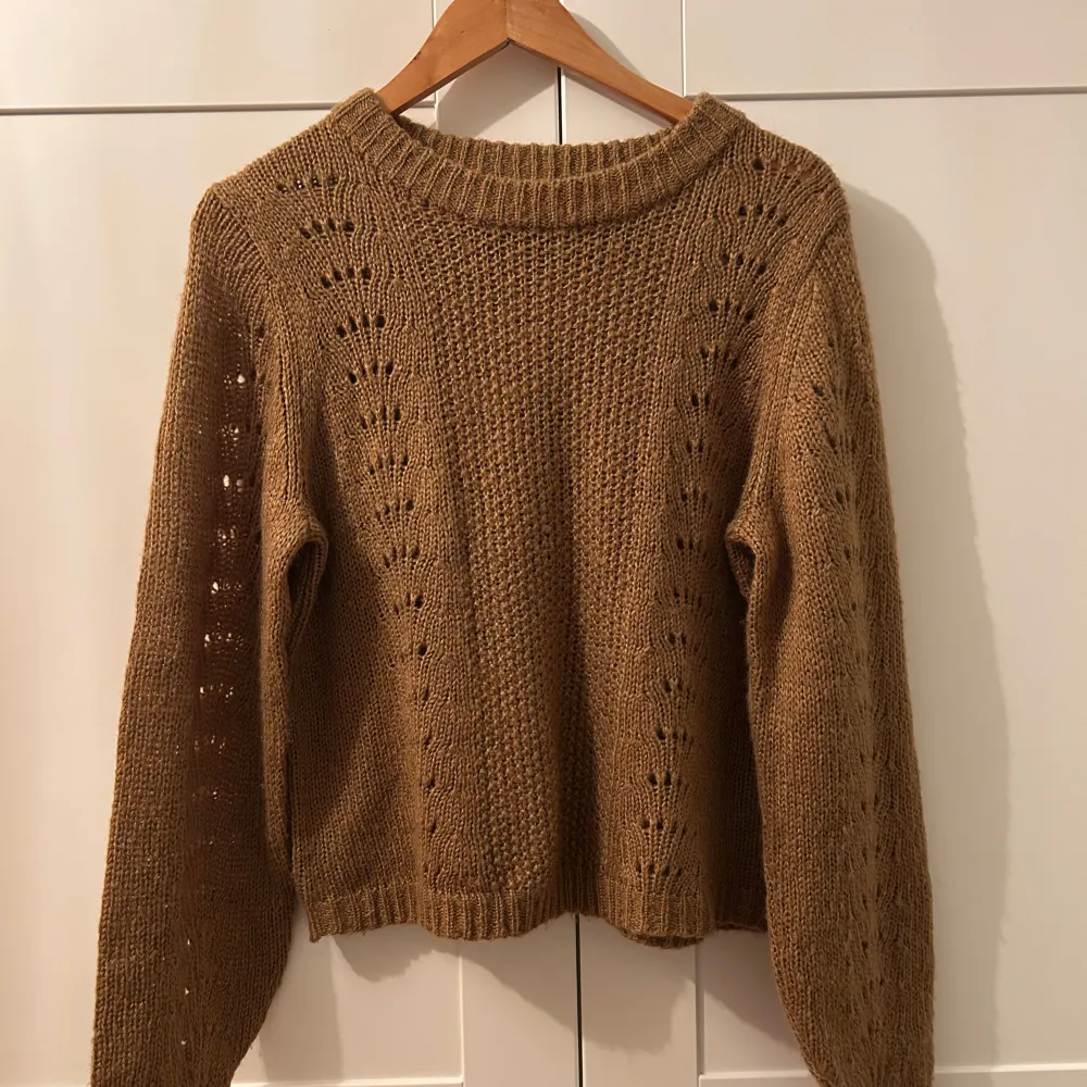Säljer en mysig brun stickad tröja med ett fint hålmönster längs ärmarna och framstycket. Perfekt för höst och vinter, den har långa ärmar och en bekväm passform. Tröjan är i mycket bra skick och passar perfekt för kyliga dagar. Helt ny men utan prislapp 🧶🍂. Neuletakit & Villapaidat.