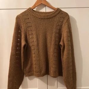 Brun stickad tröja - Säljer en mysig brun stickad tröja med ett fint hålmönster längs ärmarna och framstycket. Perfekt för höst och vinter, den har långa ärmar och en bekväm passform. Tröjan är i mycket bra skick och passar perfekt för kyliga dagar. Helt ny men utan prislapp 🧶🍂